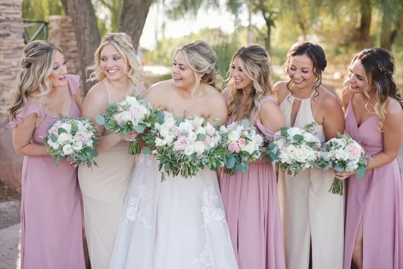 Bride with her bridesmaids in pink and champagne dresses holding white and green bouquets