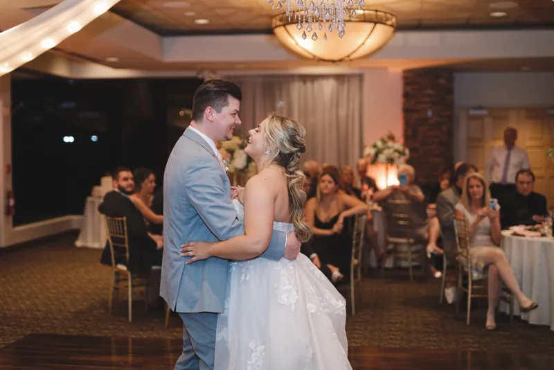 Couple dancing together in the clubhouse reception room while guests watch from their seats