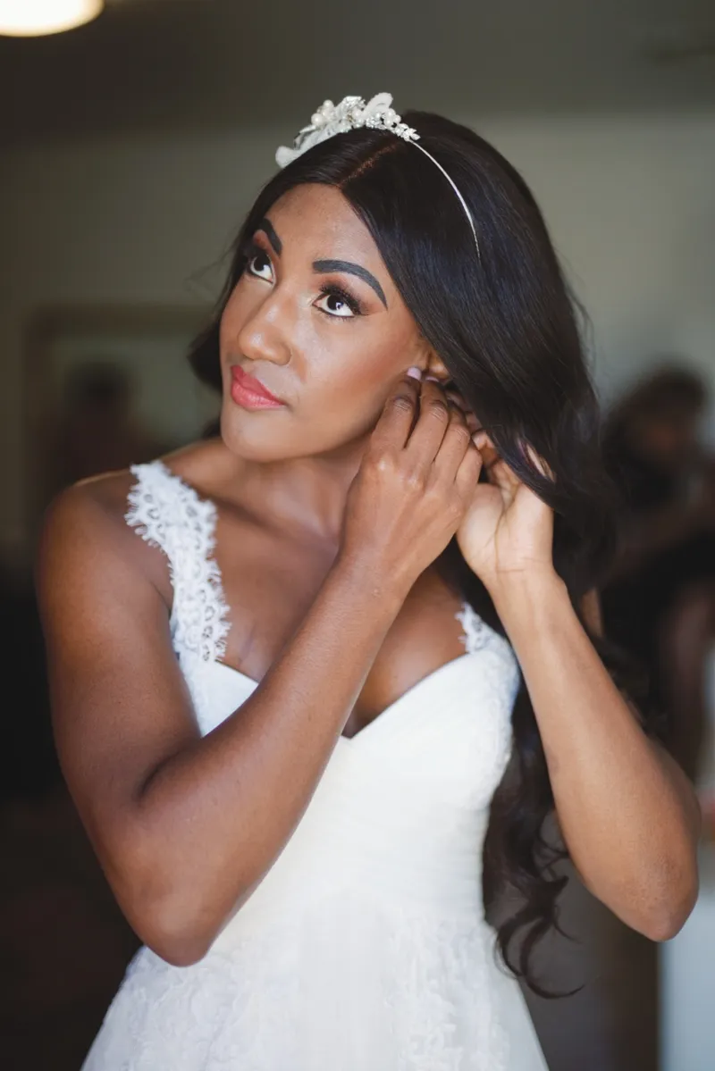 Bride in a crystal headband tucking her hair behind her ear and looking off to one side
