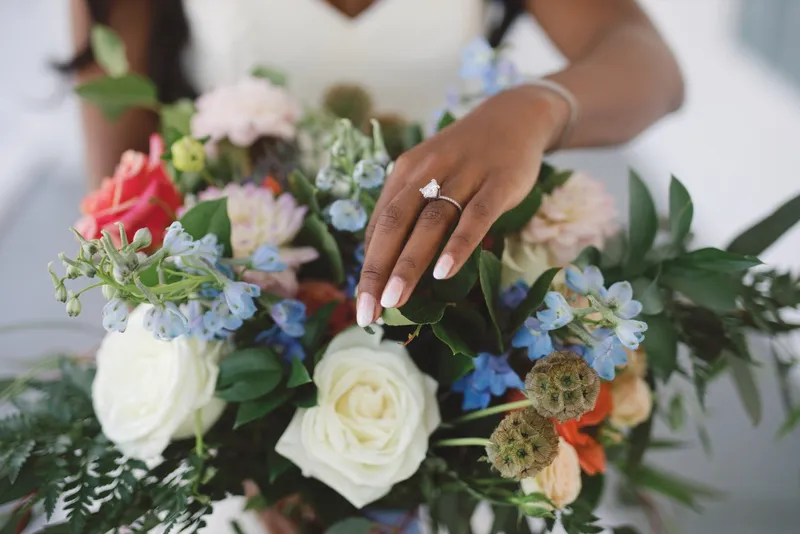 The bride's hand resting on top of her bouquet so her ring sits against the cream roses