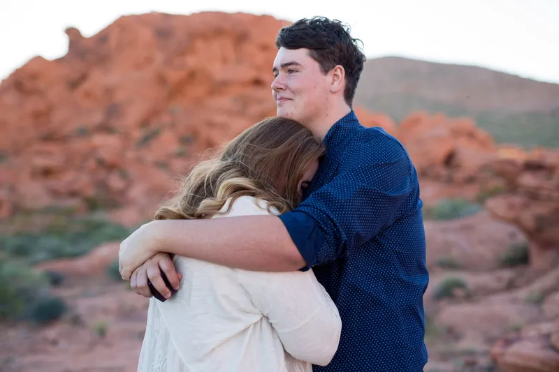 Close photo of her arms wrapped around his neck while he looks off over her shoulder
