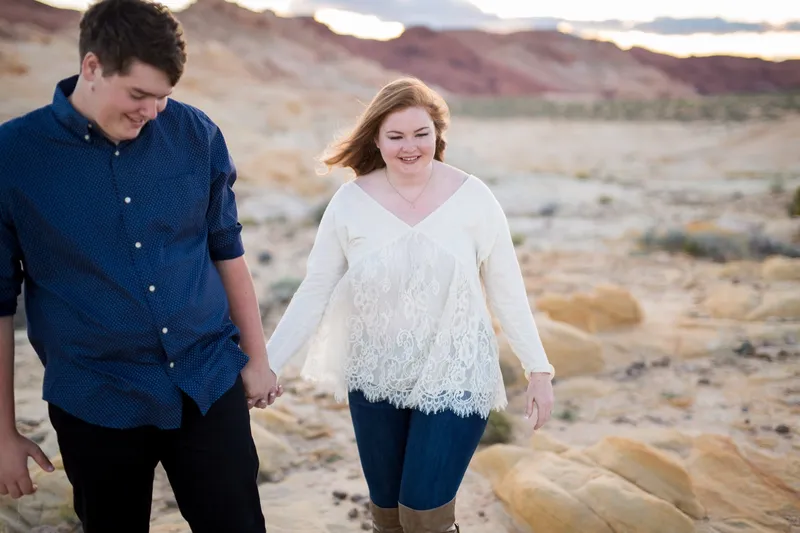 The two of them walking hand in hand across the pale rock, both of them laughing